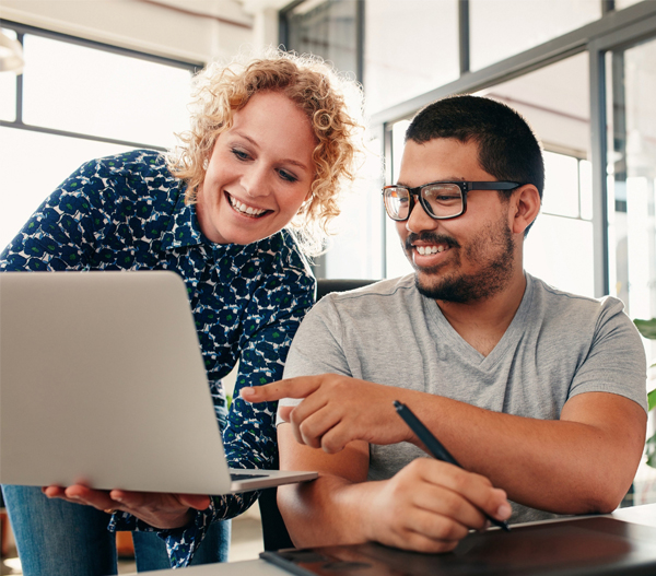 Two people smiling and looking at a laptop