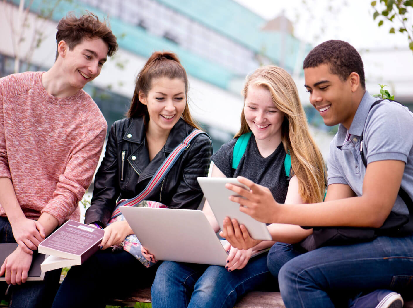 Student sitting outside looking and smiling at mobile devices