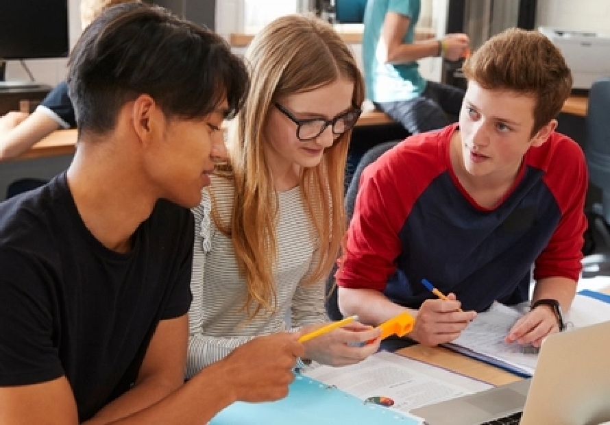 Group of students sitting at a desk looking at computer