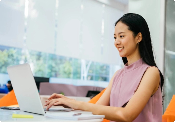 Woman working on a laptop at a desk.