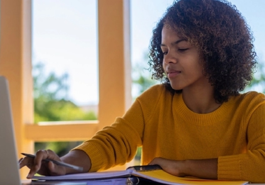 Student looking and typing on a laptop
